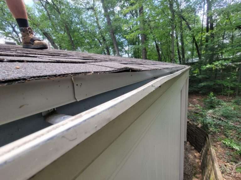 The plywood and shingle extend over the gutter causing rain to not flow into gutter.